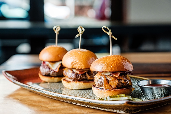 three sliders on plate in restaurant.