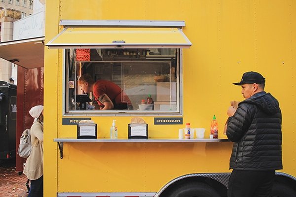 man standing near food truck ordering
