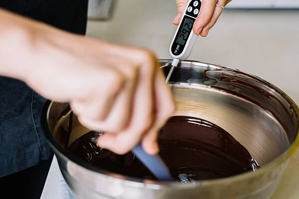 Tempered chocolate in mixing bowl with thermometer