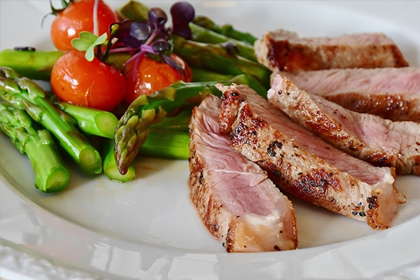 Cuts of pork chops on a plate with a variety of vegetables.