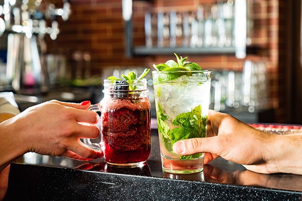 holding mocktail at bar with friends.