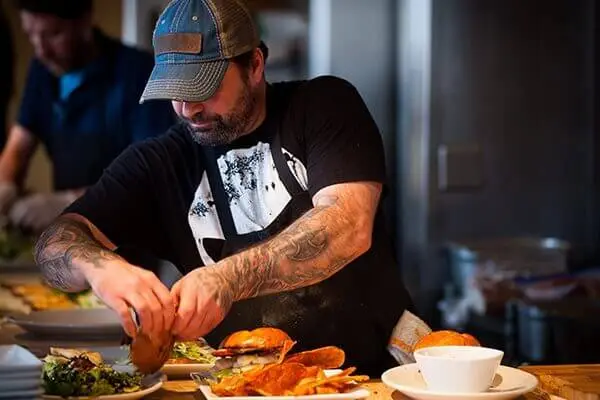Restaurant worker plating a burger at a restaurant.