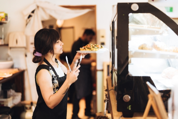restaurant worker adding food items to display rack.