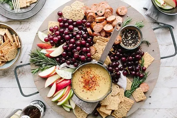 Charcuterie board of fruits, fondue, and bread.