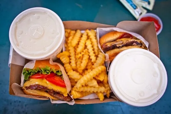 Two burgers and crinkle cut fries in a cardboard to-go container.