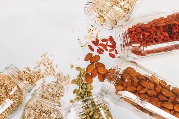 Oats and nuts pouring out of glass containers out on a countertop.