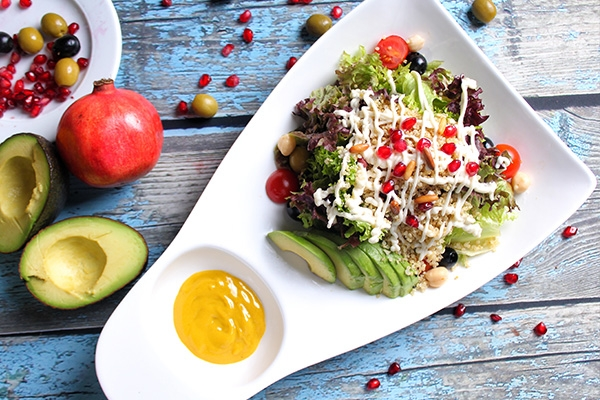 Avocado salad on a white plate with orange dressing.
