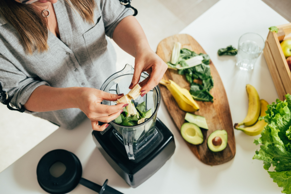 Top-view of woman preparing ingredients and putting them in a blender, making a smoothie