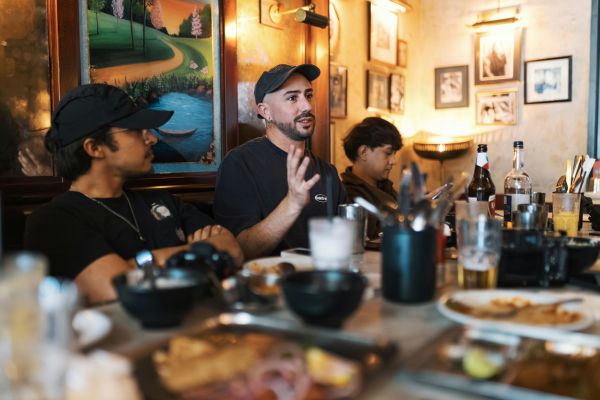 Restaurant owners and staff sitting at a table, eating and talking.