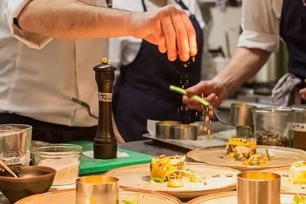 chef adding ingredients to restaurant dish.