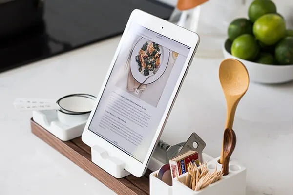 Recipe on a tablet with cooking utensils, set on a clean, white counter.