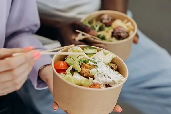 People eating out of sustainable takeout bowls.