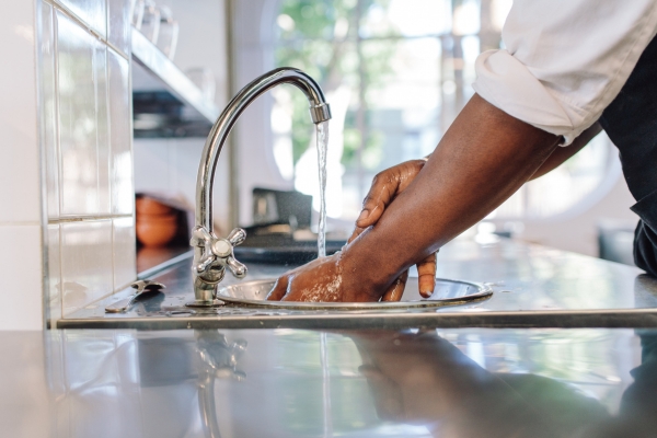 employee washing hands in sink at restaurant