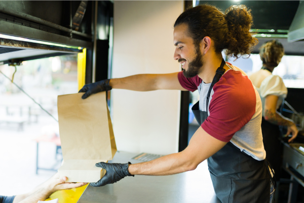 Man delivers bag of food out of food truck window