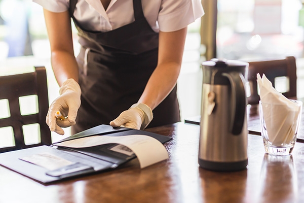 Waitstaff picking up a check from a dining table.