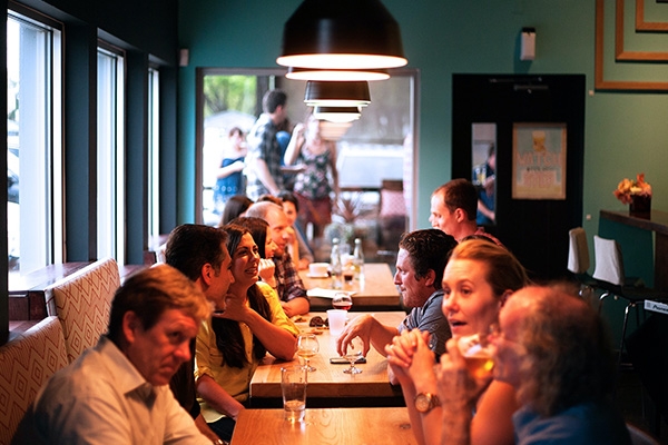Patrons sitting at tables inside of a restaurant.
