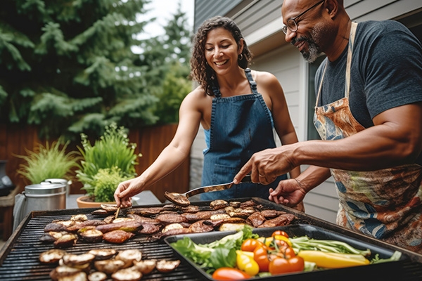 Twp people grilling chicken and vegetables on a backyard grill.
