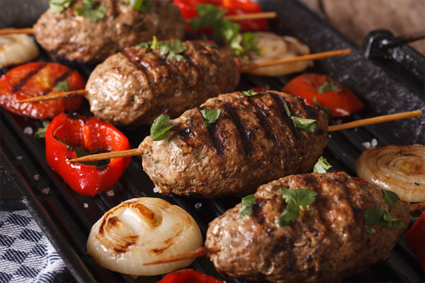 Halal meat and vegetables cooking on a grill.