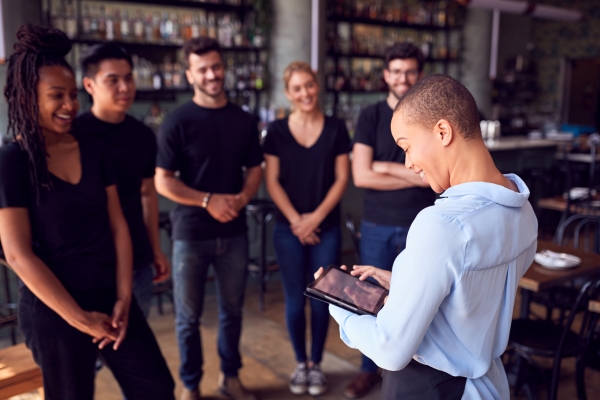 Restaurant staff having a team meeting in the front of house.