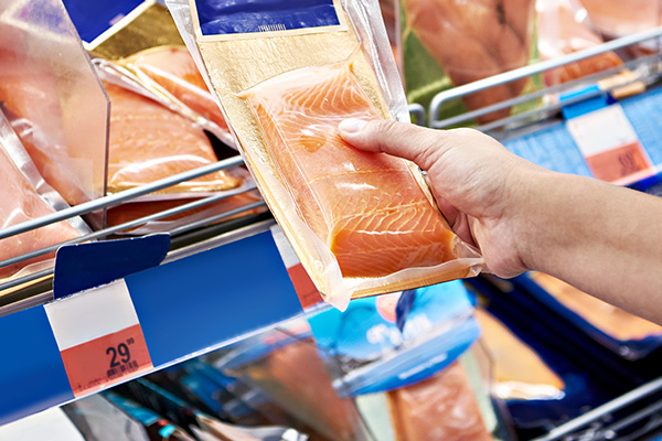 grocery shopper looking at fresh salmon in store.
