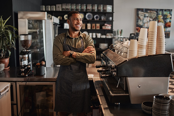 coffee shop owner standing in store with arms crossed.