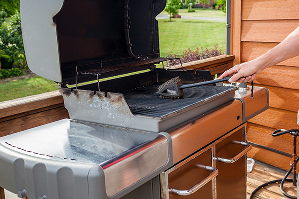 man cleaning grill with brush.