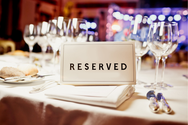 Restaurant table with RESERVED paper sign on it, surrounded by wine glasses