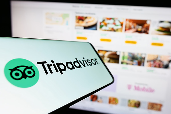 phone showing the tripadvisor app in front of desktop screen