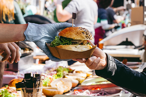 food worker handing customer a hamburger dish from food cart.