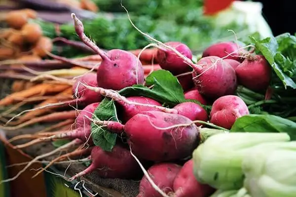 Root vegetables like beets and carrots on display at a grocery store.