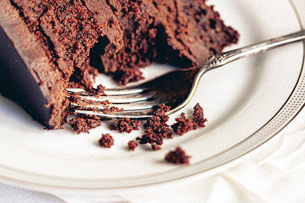 Chocolate cake and a silver fork on a white plate.