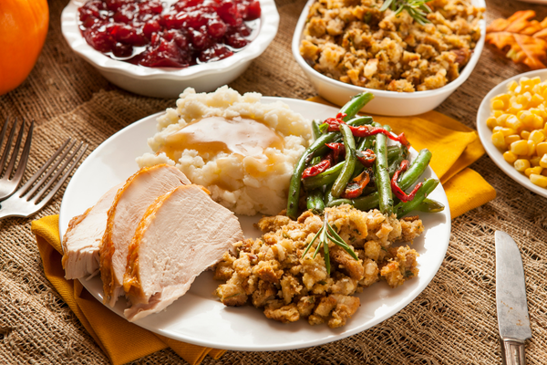 Thanksgiving dinner on a plate surrounded by other food dishes