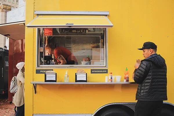 man ordering from a yellow food truck