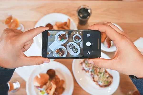 Person taking a photo of their food on a smartphone.