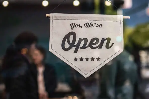 Yes, We're Open sign hanging on a window.