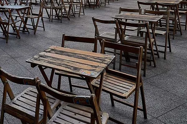 Empty wooden tables and chairs outside.