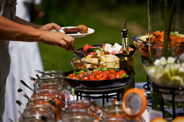 person serving food from outdoor buffet