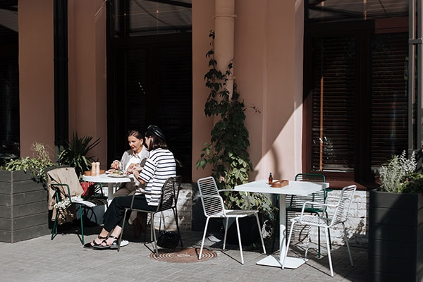 Two people sitting at a round table outside of a restaurant.
