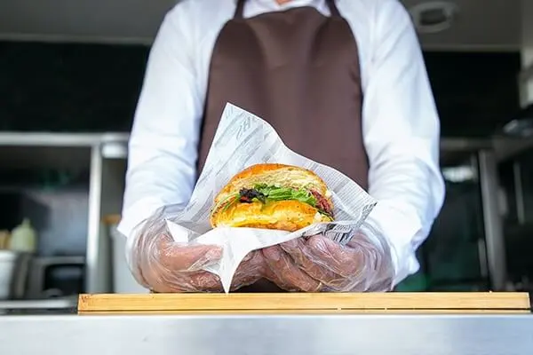 Chef wrapping a burger in paper.