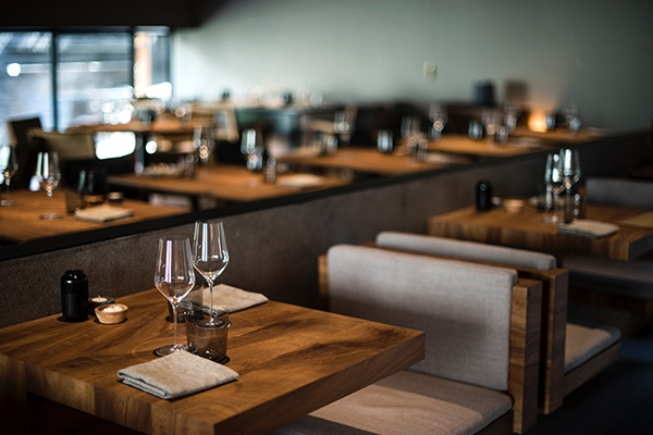 Set wooden dining tables inside of a restaurant.