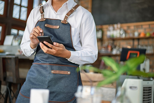 Restaurant worker working on a smartphone.