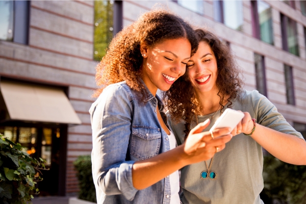 Two women looking up a restaurant on a smartphone.