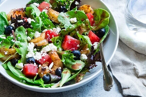Salad topped with beets, cheese, and blueberries.