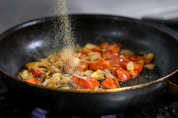 Seasoned vegetables cook on top of a cast iron skillet