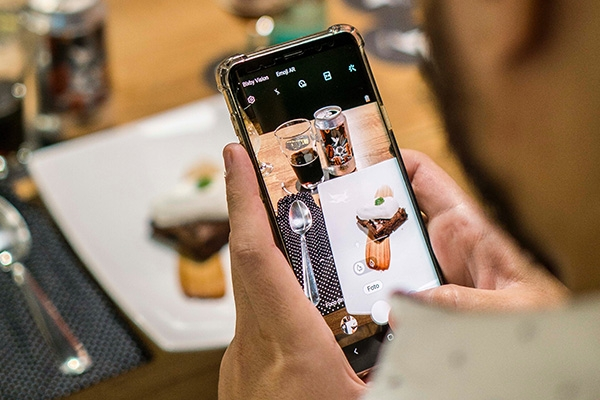 Person taking a picture of a plate of food at a restaurant.