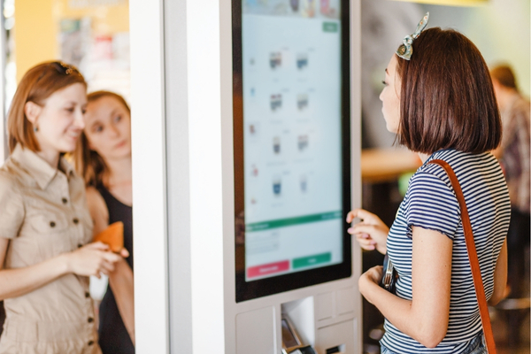 People ordering at a menu kiosk at a restaurant.