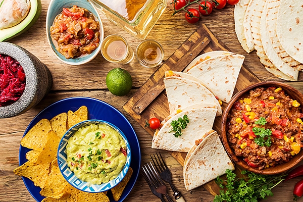 Guacamole, chips, tortillas, and salsa on a table.