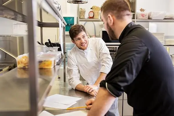 Kitchen staff talking and planning in a restaurant kitchen