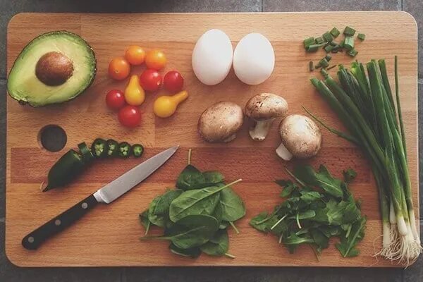 Fresh produce on a wooden cutting board with a pairing knife.