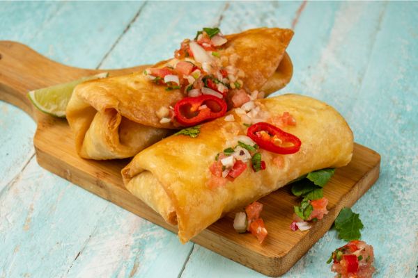 Chimichangas on a wooden plate.